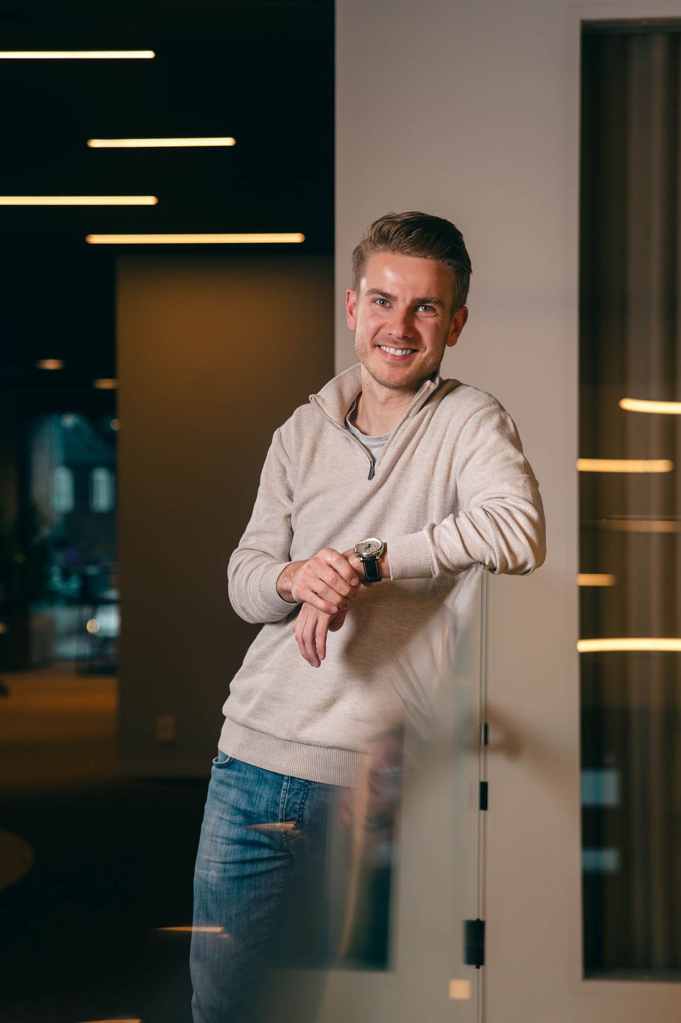 Portrett av Ole Christian Grette som står lener seg til et glassrekkverk